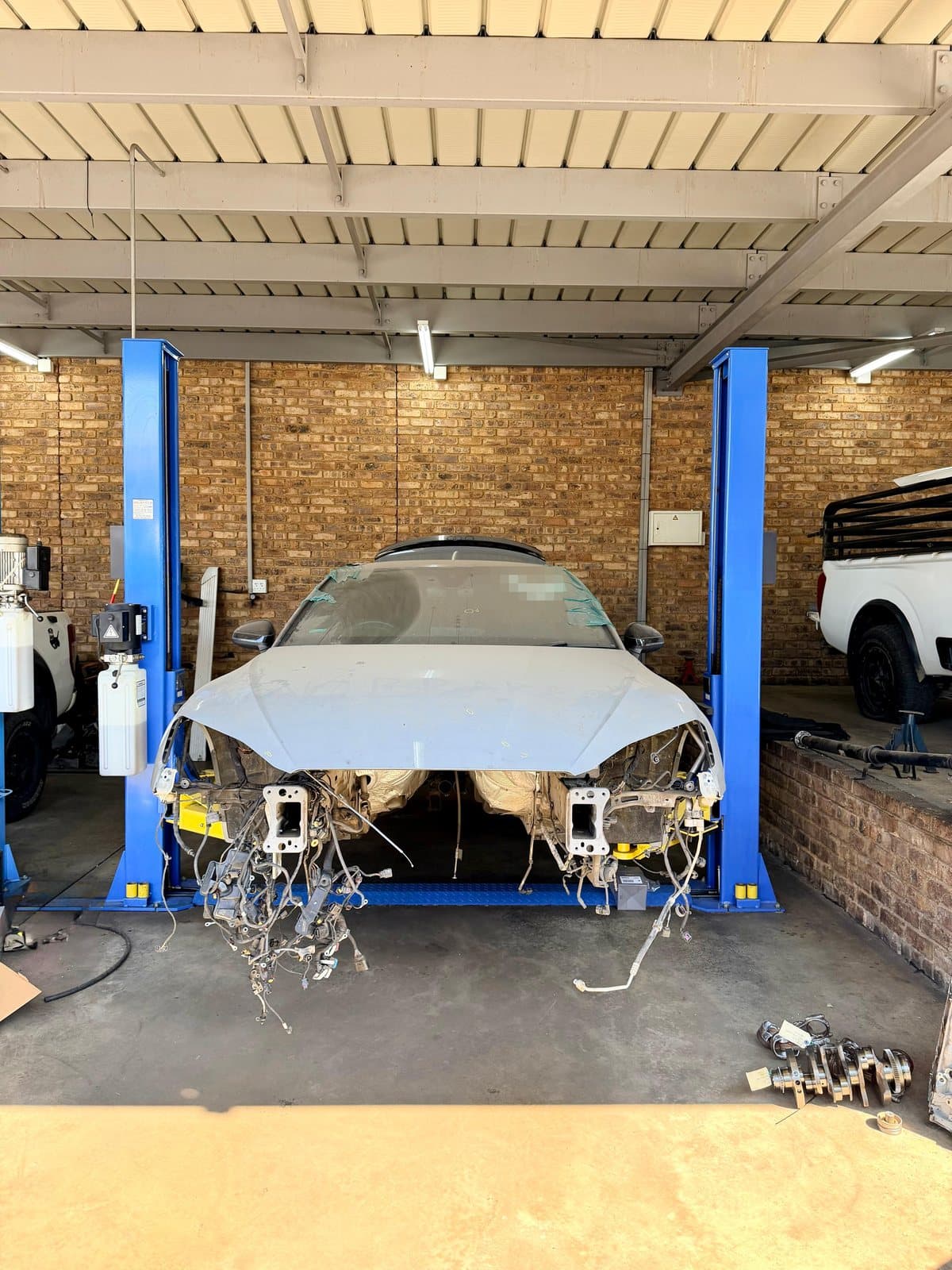 A vehicle with its front end stripped down for engine work on a two-post lift at Vision Motors, Pretoria
