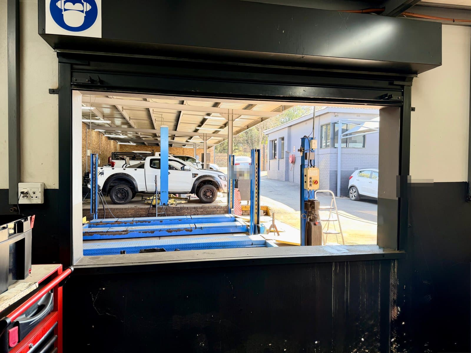 A bakkie raised on the alignment lift, seen from the workshop office at Vision Motors, Pretoria
